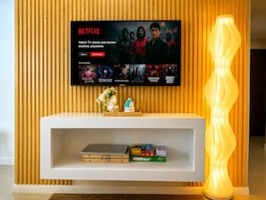 Een televisie bevestigd aan een houten muur, waarop een Netflix-interface met een selectie van populaire series wordt getoond.