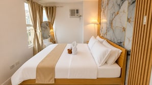 Ein Hotelzimmer mit Bett, Vorhängen, Spiegel, Lampe und Wand mit Marmoroptik.