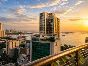 A high-rise building with a clock tower, surrounded by other buildings and a body of water.