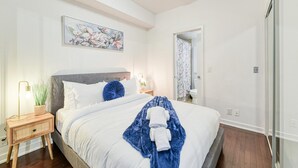Ein Schlafzimmer mit einem Bett, einem Nachttisch, einer Lampe und einem Bild an der Wand.