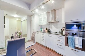 Una cocina moderna con armarios blancos, horno empotrado y microondas Panasonic.