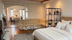 Un dormitorio con cama, sofá, una mesita de centro y una planta decorativa.