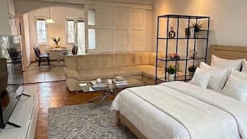 A bedroom with a bed, a sofa, a coffee table, and a decorative plant.