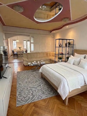 A bedroom with a bed, a sofa, a coffee table, and a decorative plant. - 120m² 4Br High-Ceiling Apartment, Ljubljana city Center & TivoliPark with Balkon (Ljubljana)