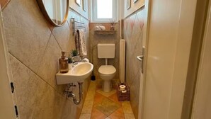 Un baño estrecho con lavamanos, inodoro y espejo.