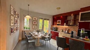 Una cocina amplia con comedor, suelo de baldosas, armarios color rojo y diversos electrodomésticos.