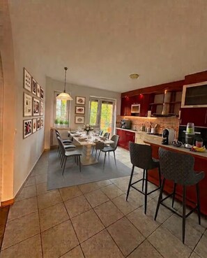 A spacious kitchen with a dining area, featuring a tiled floor, red cabinetry, and a variety of kitchen appliances. - 120m² 4Br High-Ceiling Apartment, Ljubljana city Center & TivoliPark with Balkon (Ljubljana)