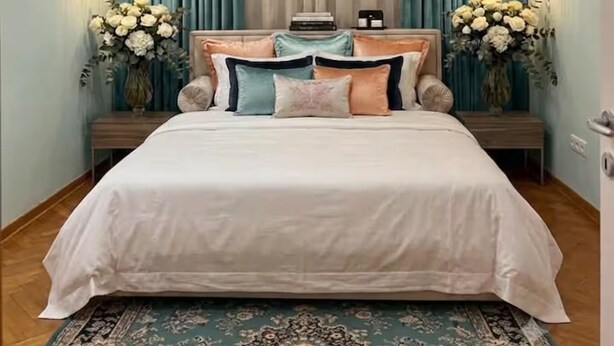 Un dormitorio con una cama grande, dos mesitas de noche, una lámpara de noche, un candelabro en el techo y una ventana con cortinas.