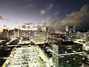 Un paisaje urbano al anochecer con edificios iluminados y un estacionamiento.