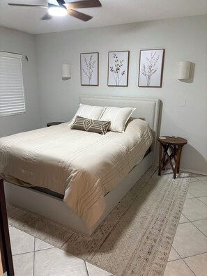 A bedroom with a bed, a bedside table, a ceiling fan, and wall-mounted light fixtures. - Charming Coastal 1-bedroom condo in wonderful Nokomis, 1 mile from the beach! (Nokomis)