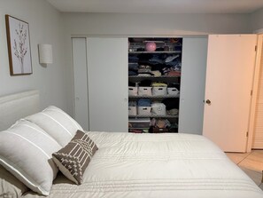 Ein Schlafzimmer mit einem Bett, Kissen, einem Schrank mit Regalen und einer Tür.