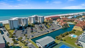 A coastal hotel with multiple buildings, a parking lot, and a marina. - Regency Towers 507E | Oceanfront | Dog Friendly | Pensacola Beach | My Beach Getaways (Gulf Breeze)