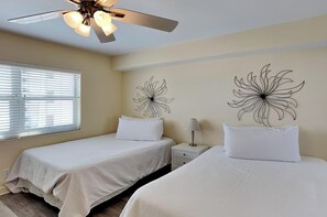 Ein Hotelzimmer mit zwei Betten, einem Deckenventilator und Wandbildern.