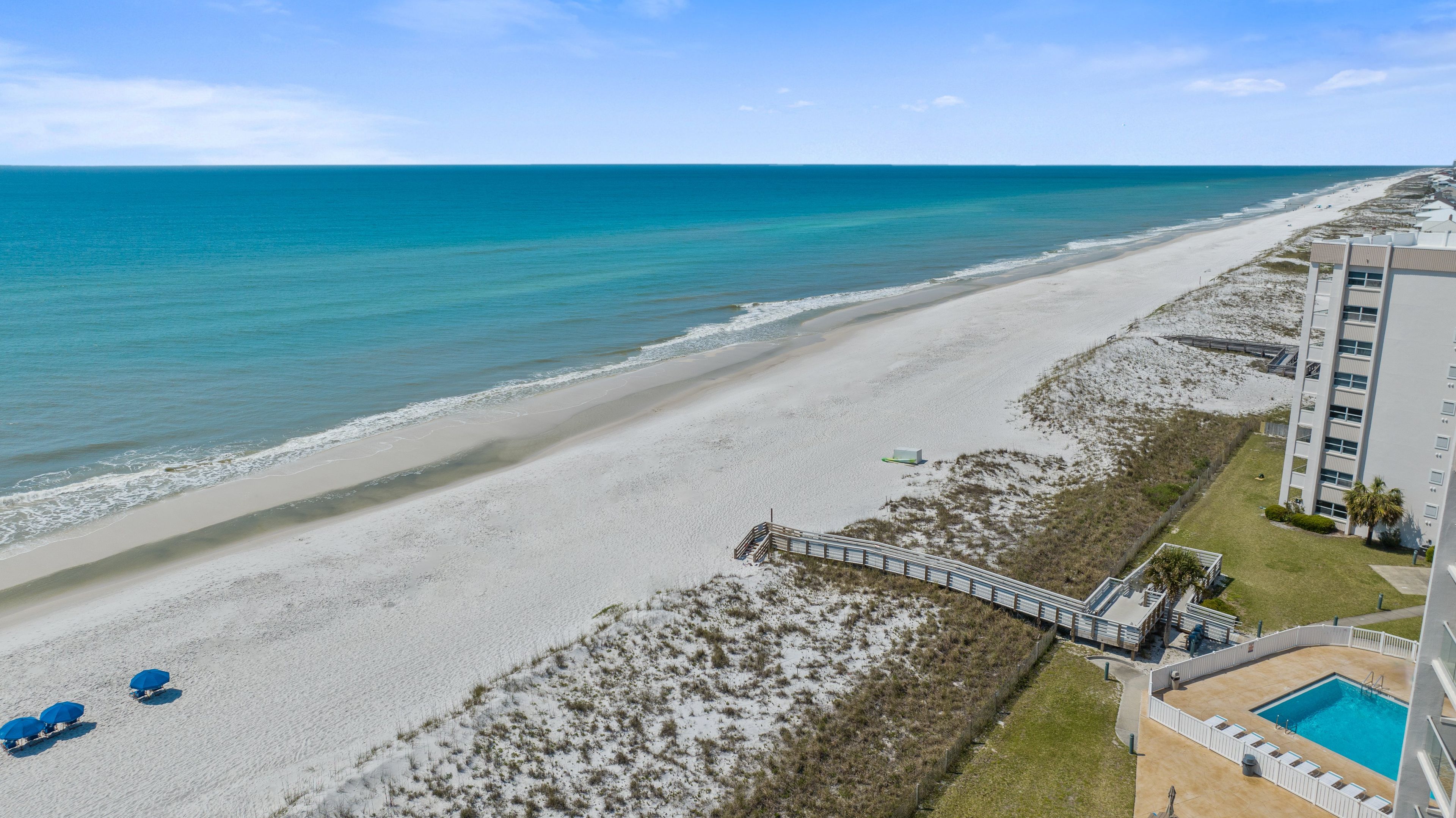 Ett hotell vid stranden med en pool, en strandpromenad och utsikt över havet.