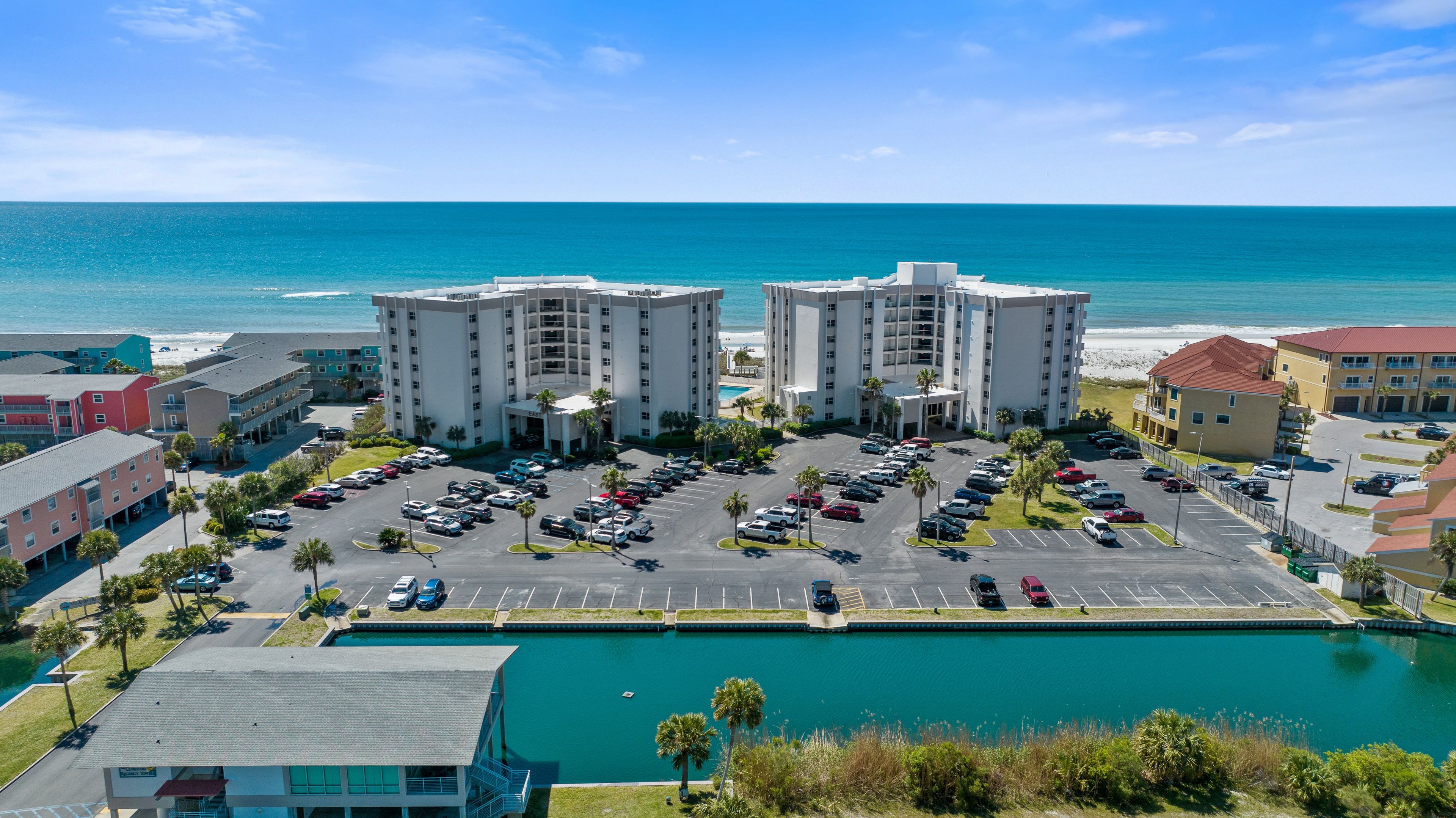 Ein Hotel mit Parkplatz, Schwimmbad und Blick auf Strand und Meer.