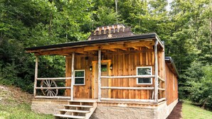 Ein rustikales Holzhaus mit Veranda, Wagenrad und einem Schild mit der Aufschrift 'SHERIFF'.