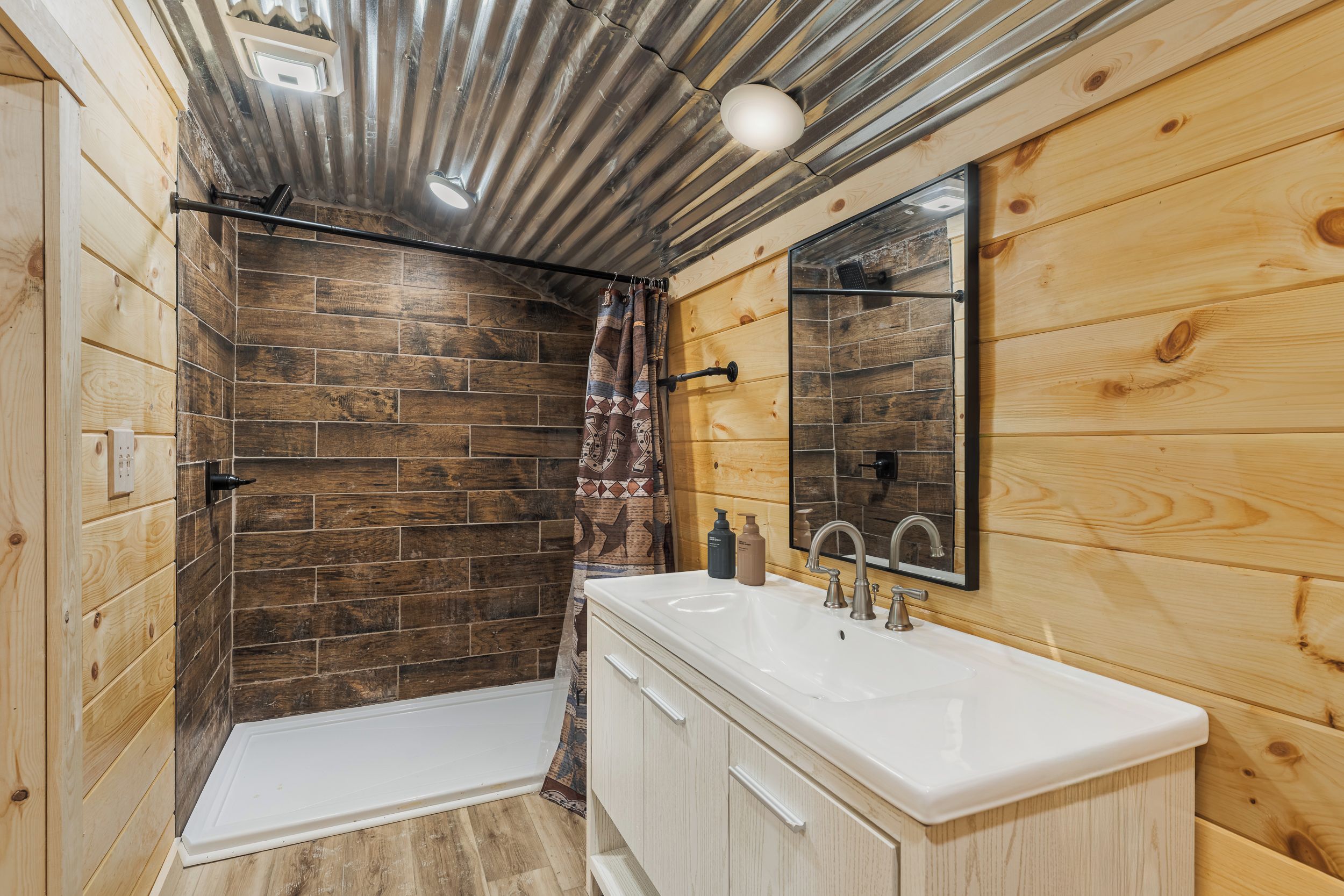 A bathroom with a shower, a sink, and a mirror.
