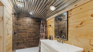 Ein Badezimmer mit Dusche, Waschbecken und Spiegel.