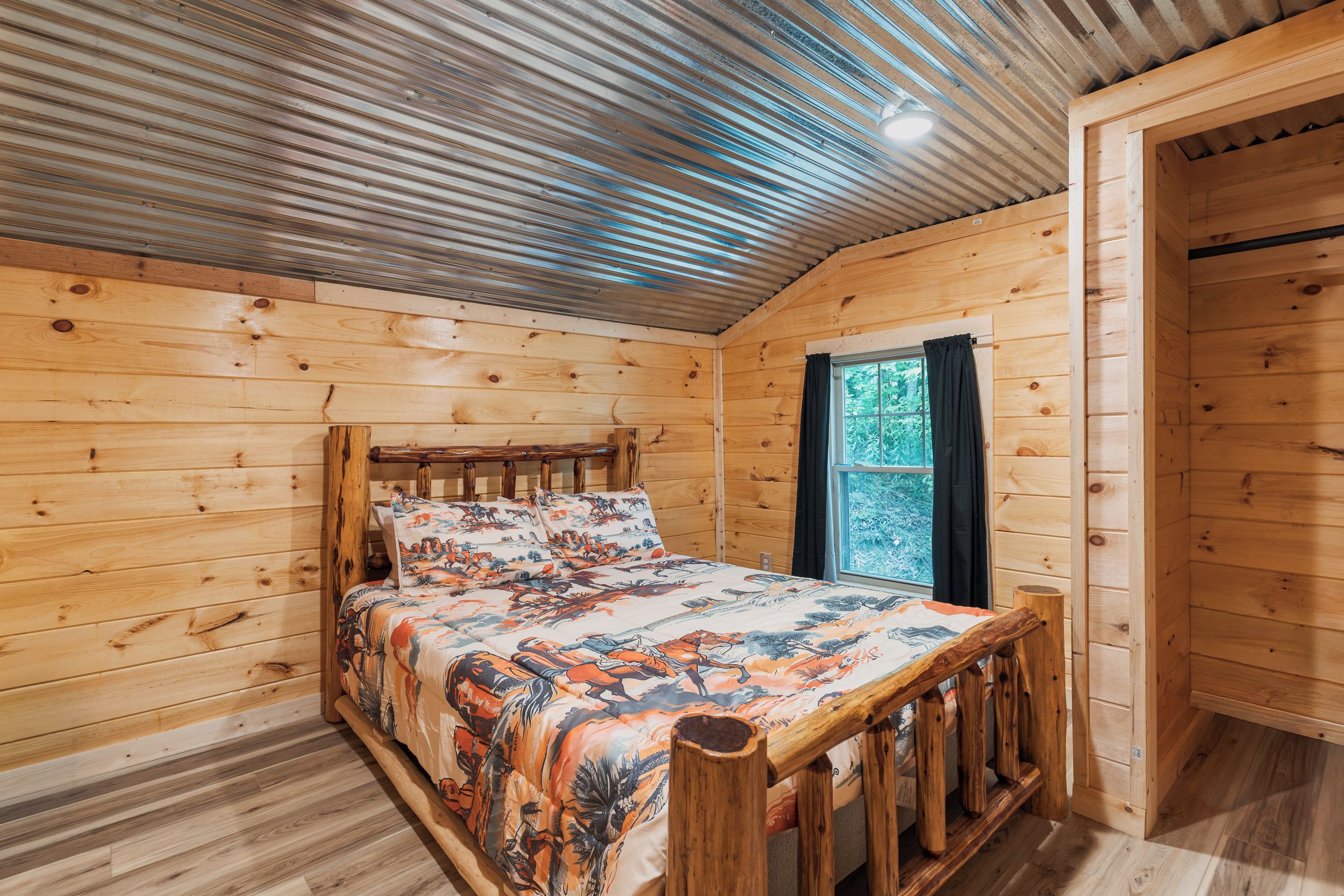 A wooden cabin room with a bed, a window, and a door.