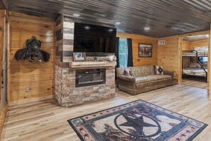 A cozy cabin interior with a stone fireplace, a sofa, and a bunk bed. - Welcome to the Sheriff's Office (Stanton)