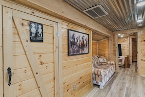 A wooden interior with a restroom sign, a framed horse painting, and a sofa. - Welcome to the Sheriff's Office (Stanton)