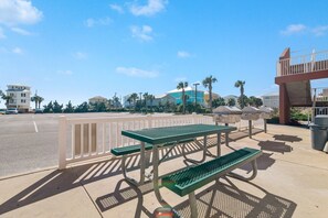 A parking area with picnic tables and a white fence. - Sanibel 902 | Gulf View | Outdoor Pool, Hot Tub, & Sauna | My Beach Getaways (Gulf Shores)