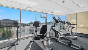 Ein Fitnessstudio mit unterschiedlichen Trainingsgeräten, großen Fenstern und Blick auf die Stadt.