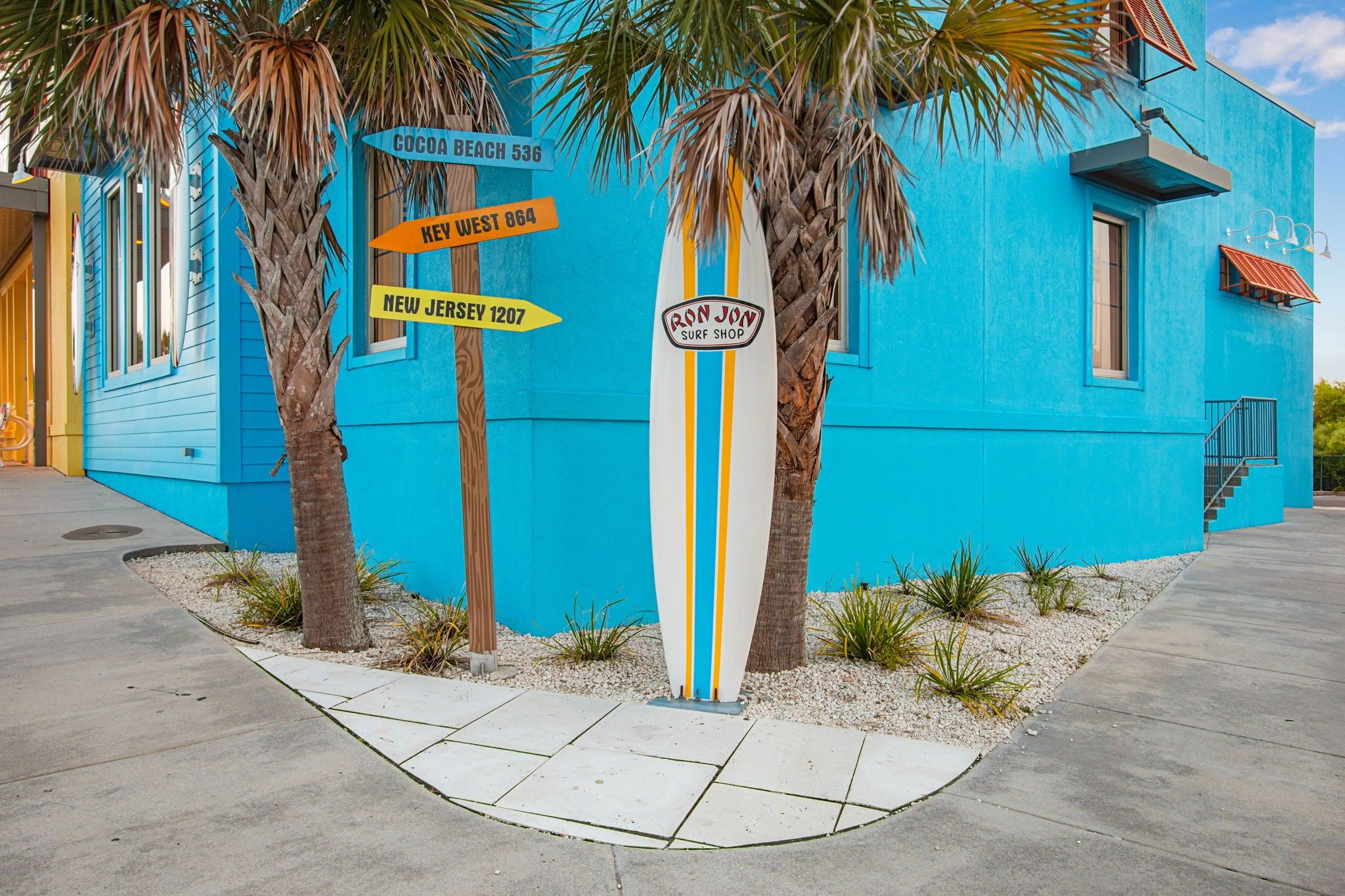 A vibrant blue building with directional signs for Cocoa Beach, Key West, and New Jersey.