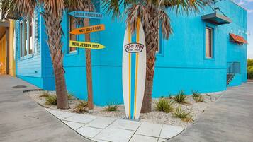A vibrant blue building with directional signs for Cocoa Beach, Key West, and New Jersey.