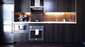 Eine moderne Küche mit dunklen Holzschränken, Edelstahlgeräten und einer weißen Arbeitsplatte.