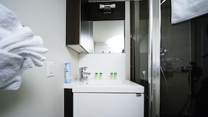 Ein Badezimmer mit einem weißen Waschbecken, einem Spiegel und einer Duschkabine.