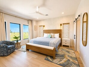 Una camera da letto con un letto, comodini, una sedia, una ventola a soffitto e vista sull'esterno.