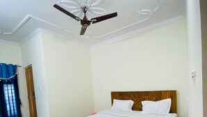 Une chambre d’hôtel avec un lit, un ventilateur de plafond et un sol à carreaux.