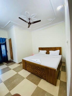 A hotel room with a bed, a ceiling fan, and a checkered floor. - Hotel KK Hld  (Haldwani)