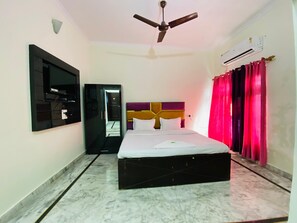 A hotel room with a bed, a ceiling fan, an air conditioning unit, a television, and a wardrobe. - Hotel KK Hld  (Haldwani)