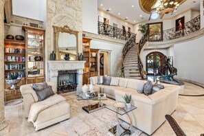 A spacious living room with a fireplace, a large sofa set, and a grand staircase. - The Palazzo | Waterfront | Walk to Beach | Luxury Villa (Fort Lauderdale)