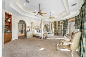 A spacious bedroom with a large bed, two chairs, a vanity, and a ceiling fan. - The Palazzo | Waterfront | Walk to Beach | Luxury Villa (Fort Lauderdale)