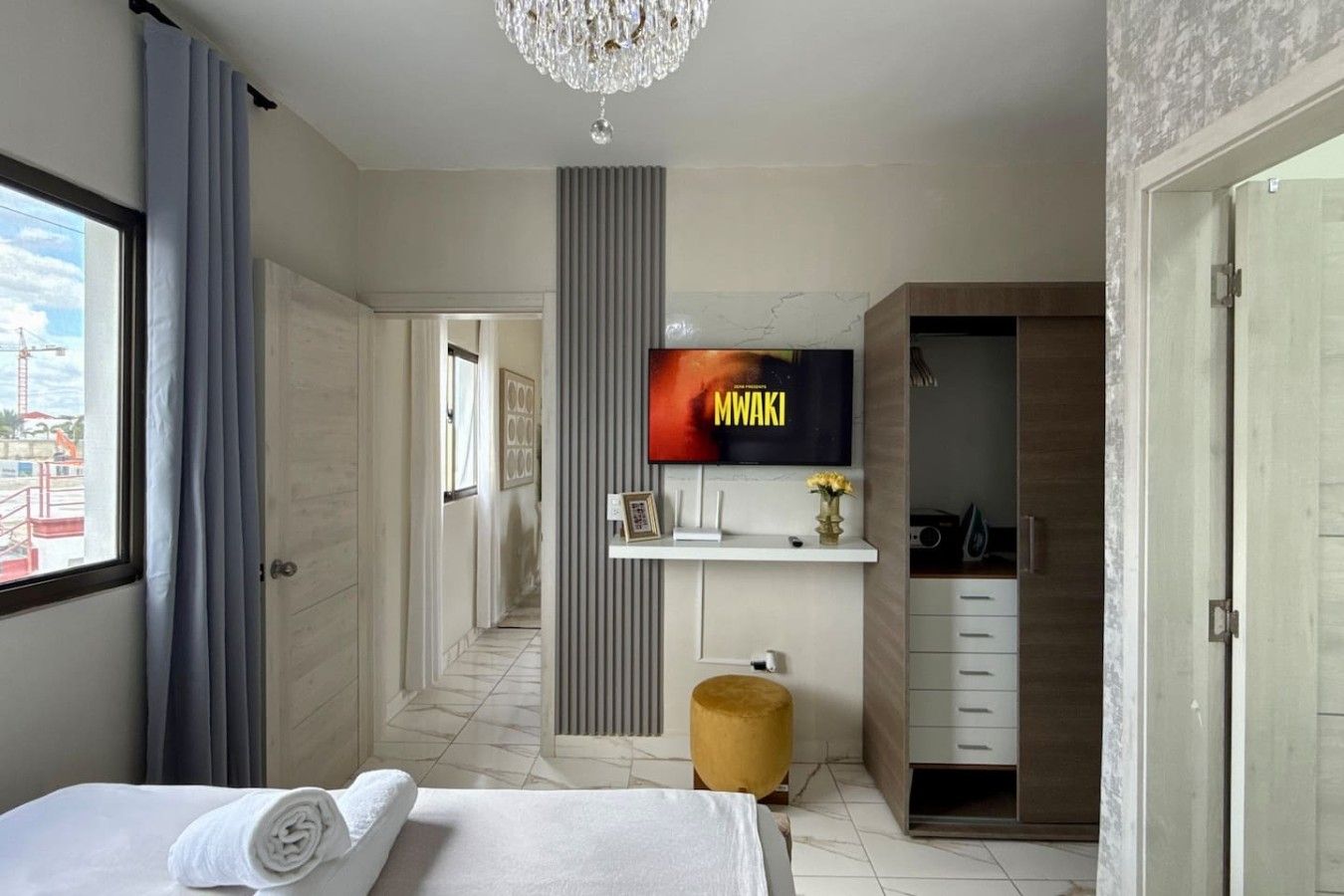 A modern hotel room with a bed, a TV, a desk, and a wardrobe.