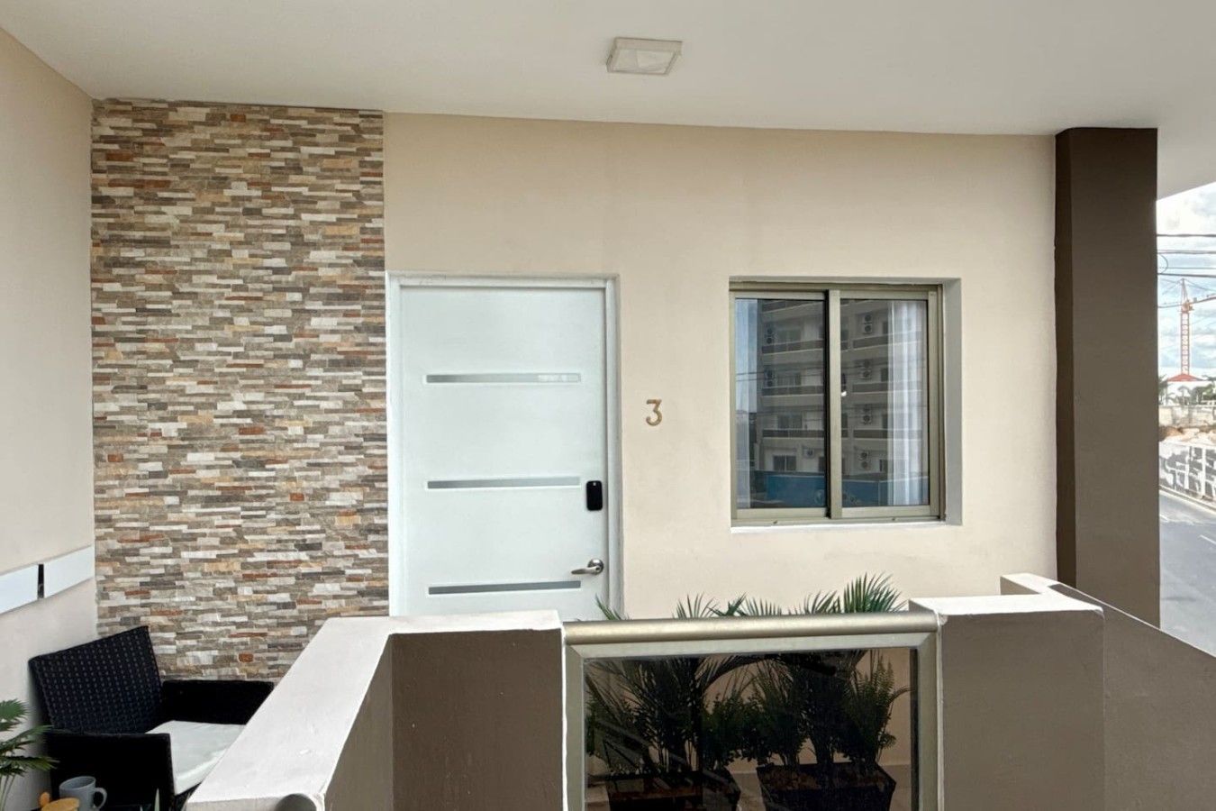 A balcony with a stone wall, a white door, and a window.
