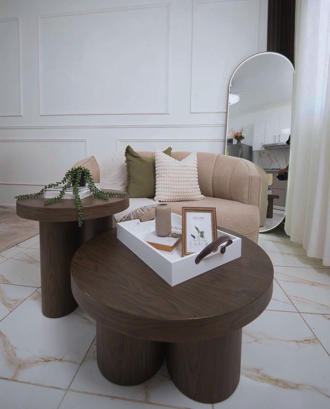 A modern living room with a round coffee table, a sofa, and a side table with a plant.