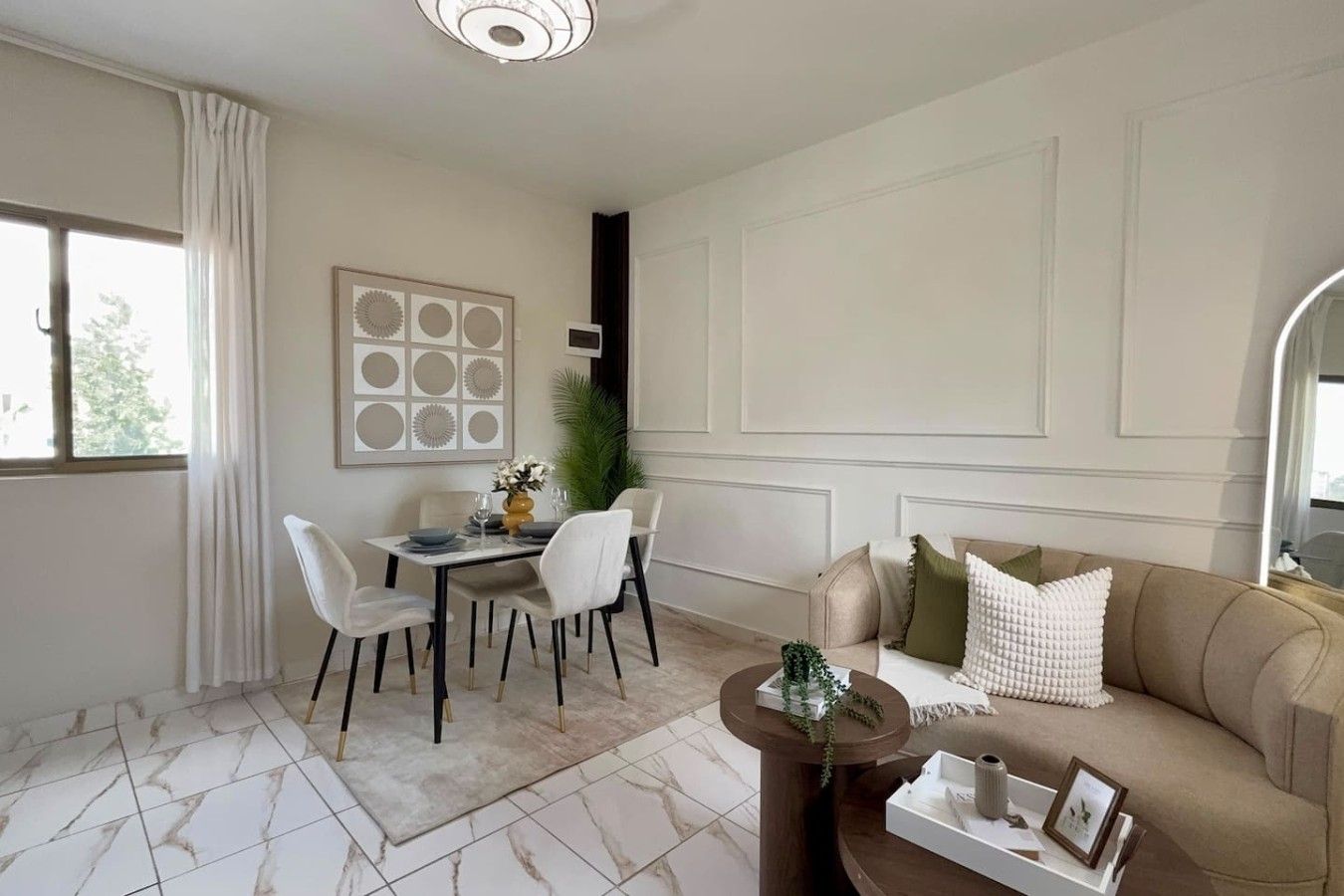 A living room with a dining area, a sofa, a coffee table, and a large window with curtains.