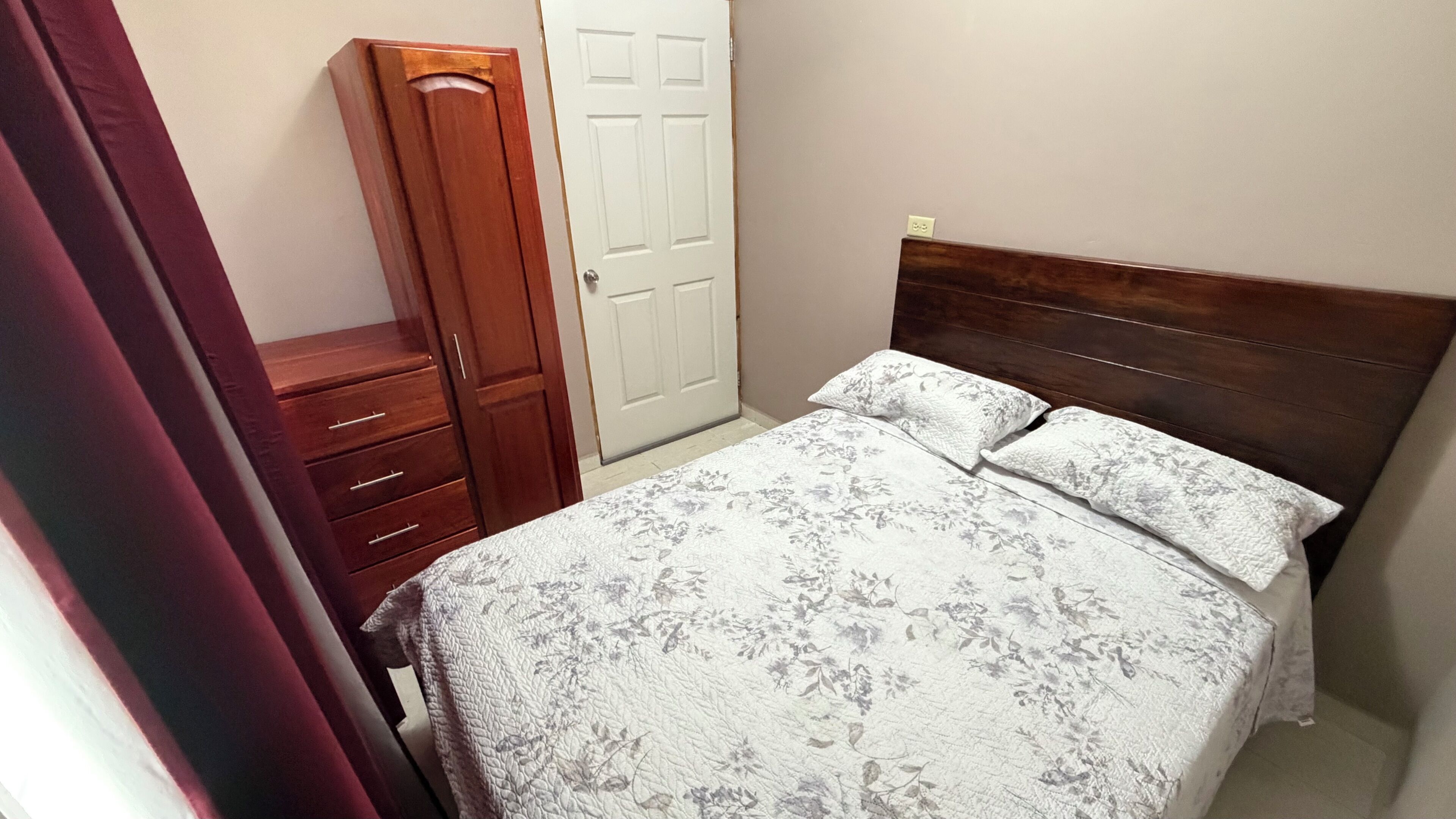 A bedroom with a bed, a wardrobe, and a door.