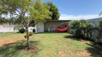 A backyard with a hammock, potted plants, and a small patio area.