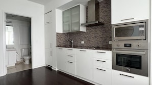Eine moderne Küche mit weißen Schränken, einer Ziegelrückwand und Edelstahlgeräten, darunter eine Mikrowelle und ein Backofen.