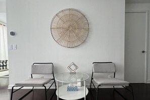A room with two chairs, a small round table, and a wall-mounted decorative piece.