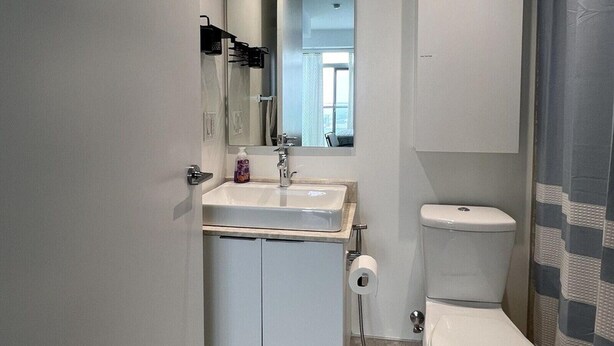 Ein kleines Badezimmer mit einem weißen Waschbecken, Spiegel und WC.