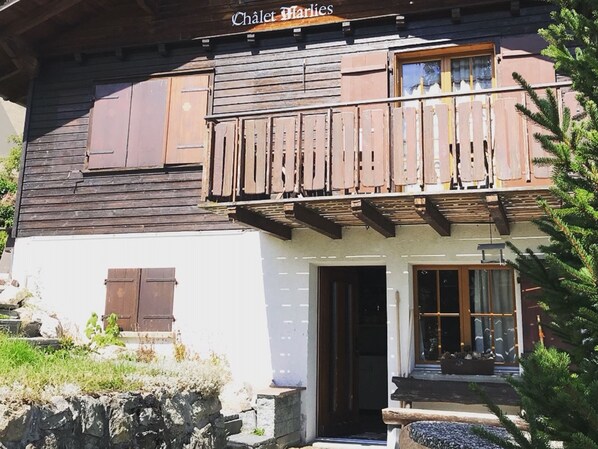 A chalet with a wooden balcony, a door, and a window.