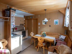 Eine kompakte Küche mit Holzausstattung, einem Esstisch mit Stühlen und einem kleinen Kühlschrank.