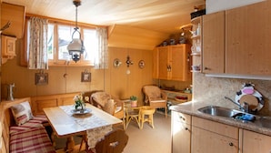 Interior acolhedor de uma cabana, com área de jantar, cozinha e espaço de estar.