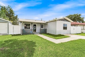 A single-story house with a front porch, a garage, and a small attached shed. - 🌸Pinellas Paradise - 4BR Pinellas Park home with pool| Sleeps 10 🌸 (Pinellas Park)